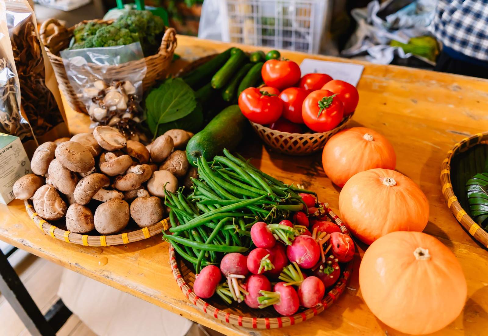 Market table with fresh produce: mushrooms, green beans, radishes, tomatoes and pumpkins